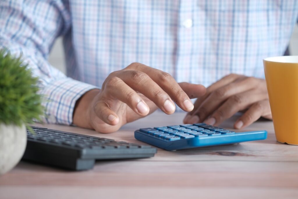 Business owner reviewing ad spend and budgets on a calculator